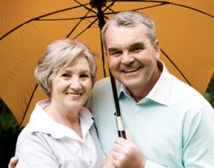 senior couple smiling together under umbrella